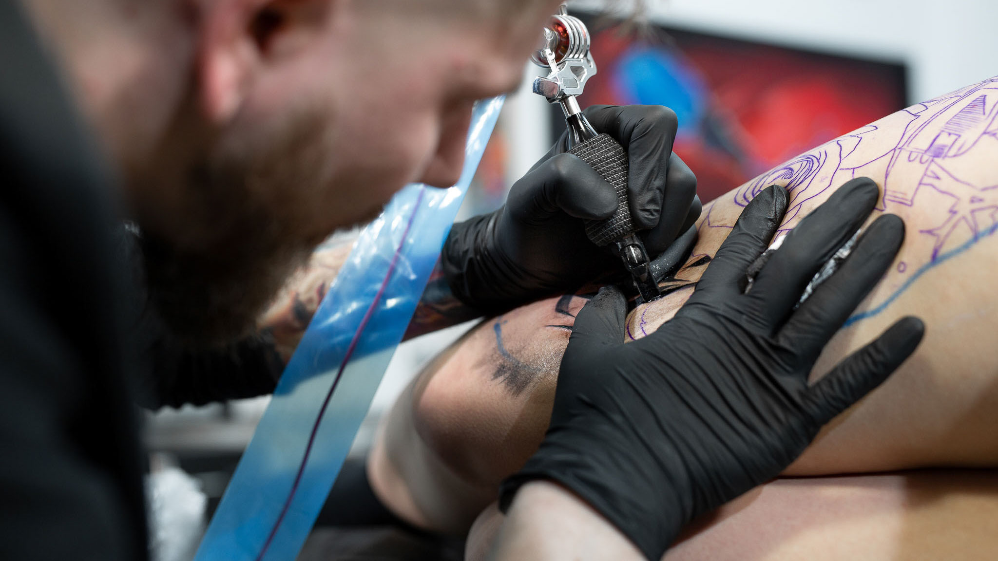Tatuerare gör en tatuering på en persons ben.